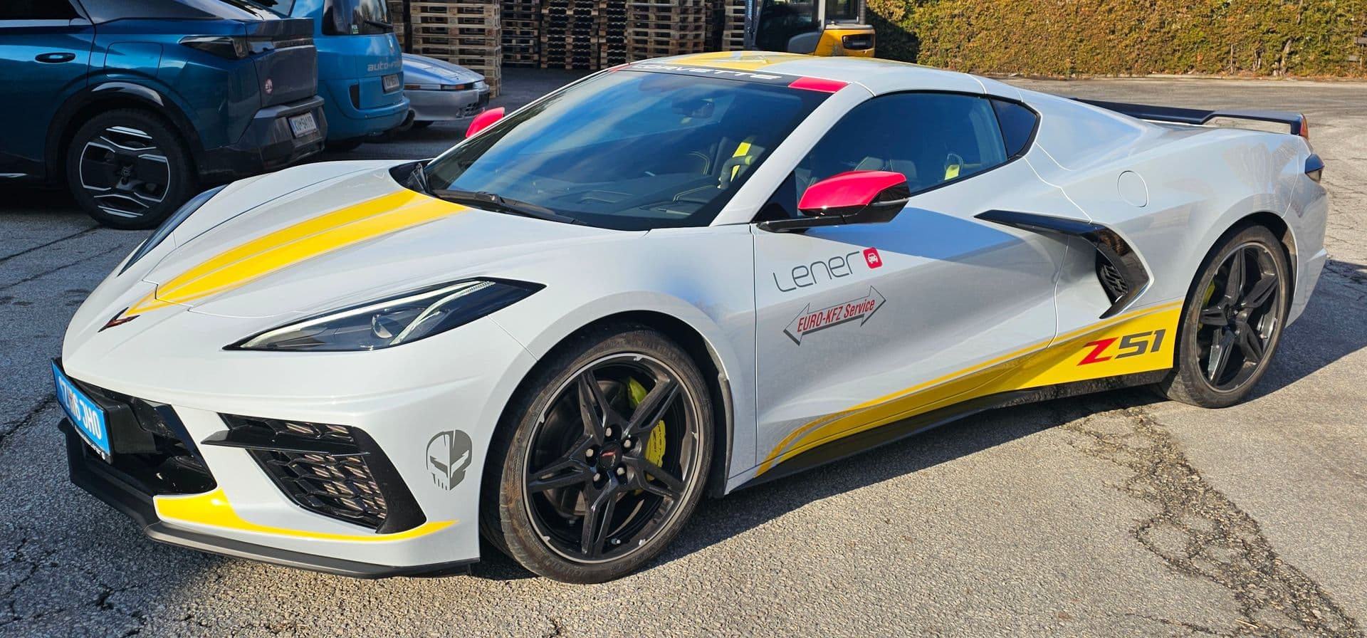 Hellgraue Chevrolet Corvette C8 mit gelben Zierstreifen, Z51-Signet und Beschriftung eines KFZ-Betriebs
