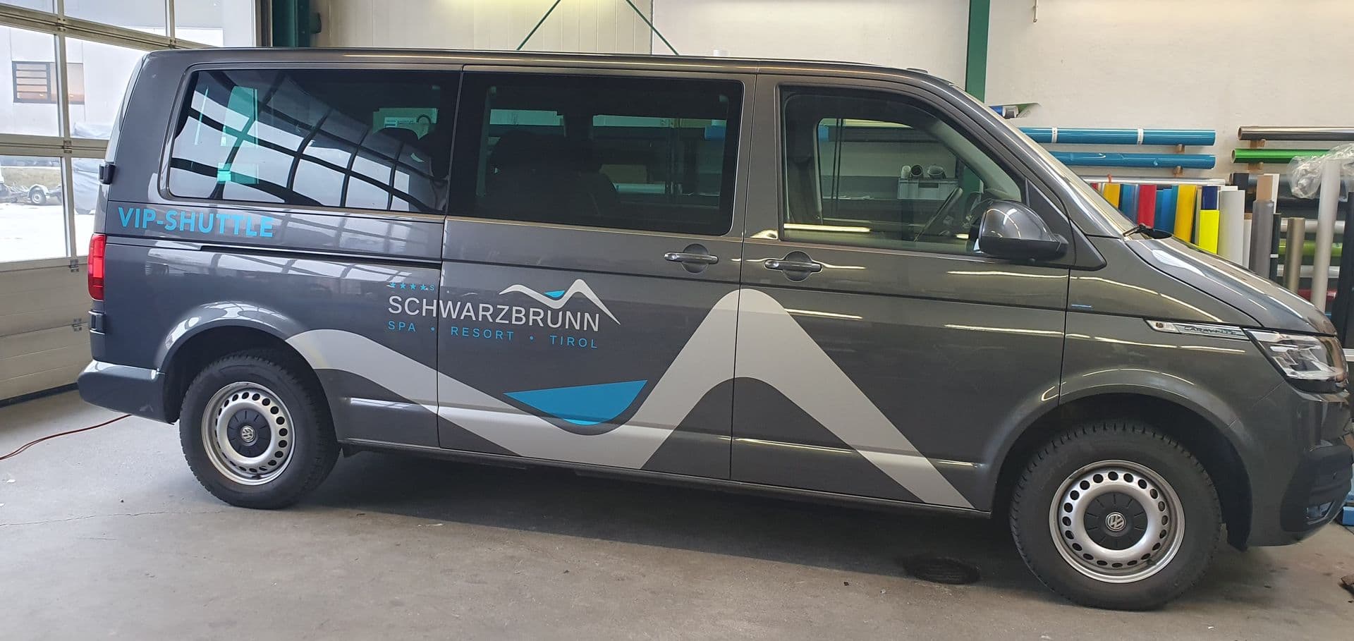Anthrazitfarbener VW Transporter als Hotel-Shuttle beschriftet, in der Werkstatt