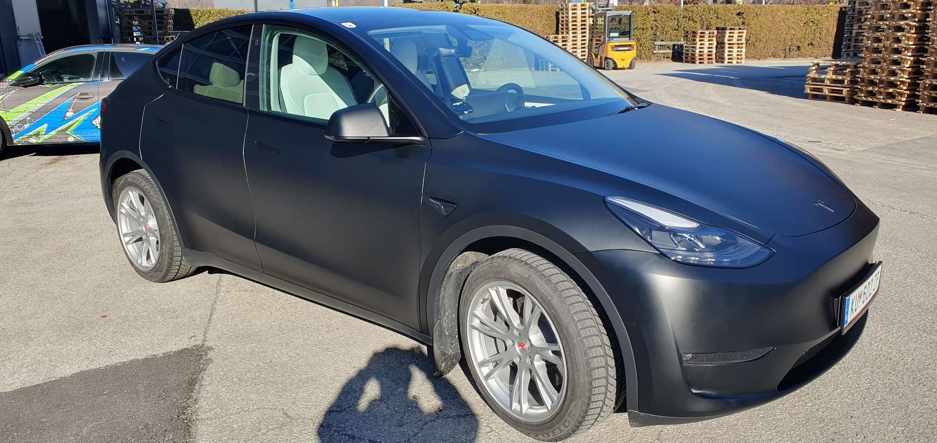 Mattschwarz folierter Tesla Model Y in der Frontansicht auf dem Betriebsgelände