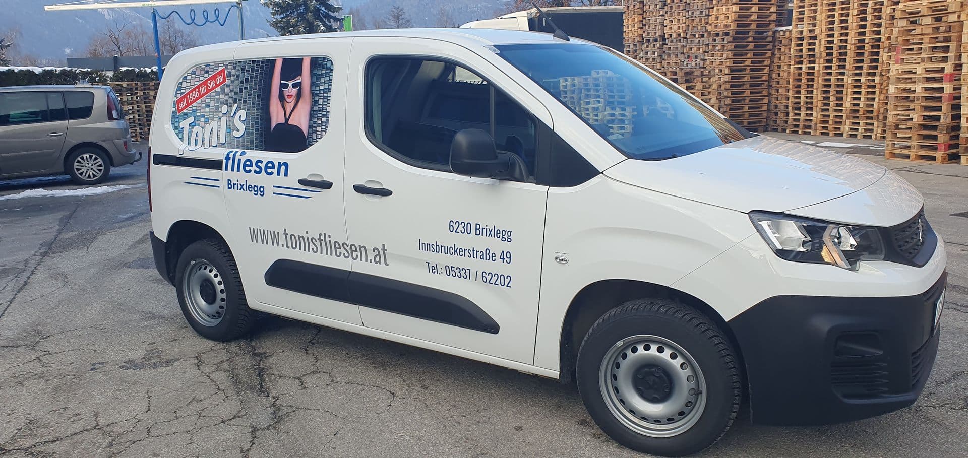 Weißer Peugeot Partner mit blauer Beschriftung eines Fliesenlegerbetriebs bei winterlichem Wetter